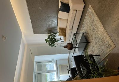 Modern lounge area with a cream sofa, textured rug, and warm integrated ceiling lighting.