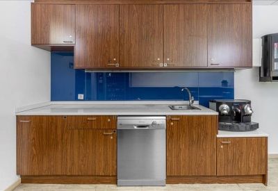 Modern kitchenette with dark wood cabinetry and a blue glass backsplash.