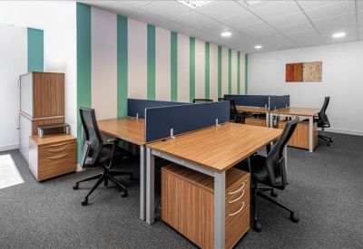 Shared office space with wooden desks and a blue and green striped feature wall.