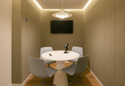 Small private meeting pod with acoustic wall panels and a round white table.