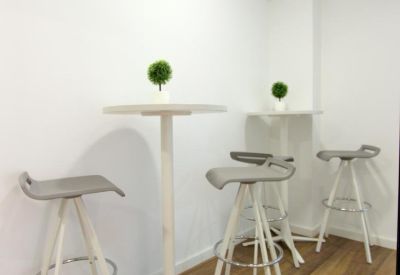 Breakout area featuring tall white tables and stylish grey bar stools.