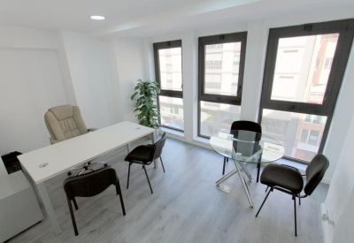 Private office suite with a white desk, executive chair, and large windows.