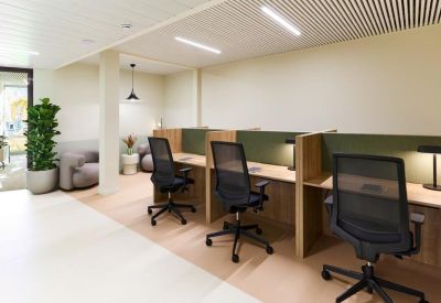 Modern coworking space with wooden desks, ergonomic chairs, and privacy dividers.