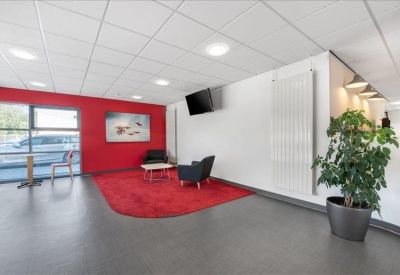 Vibrant communal lounge area with a red accent wall, red rug, and comfortable armchairs.