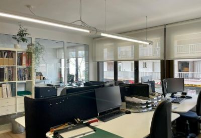 Modern open-plan office with multiple workstations and sleek linear lighting.