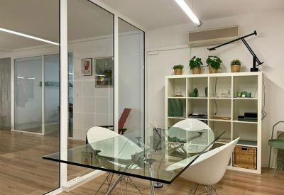 Glass-walled meeting room with a transparent table and white designer chairs.