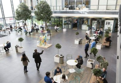 Spacious open-plan communal hub with indoor trees and various seating areas.