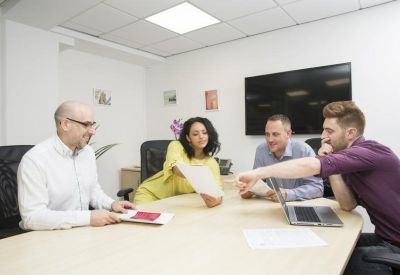 Four professionals collaborating around a light wood table in a bright office space.