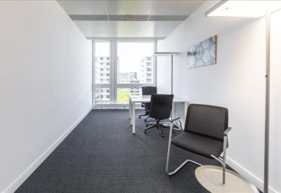 Narrow two-person office with floor-to-ceiling windows and grey carpet.