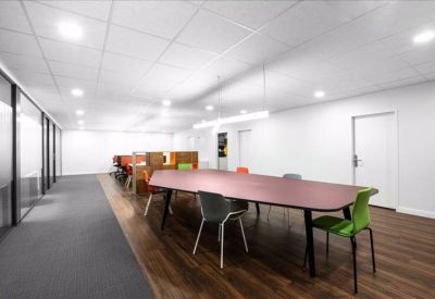 Spacious coworking area with a long purple table and bright green chairs.