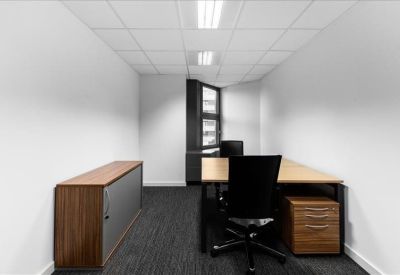 Private two-person office suite with wooden desks and grey carpeting.