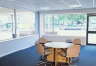Bright meeting area with a round table and four tan chairs surrounded by large windows.