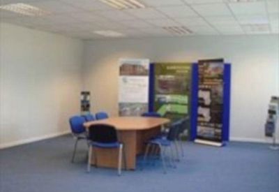 Meeting room with a central wooden table, blue chairs, and informational display banners.