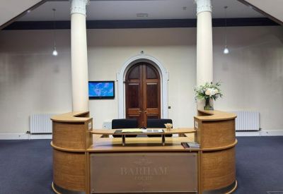 Reception area featuring a curved wooden desk, white pillars, and a central arched doorway.