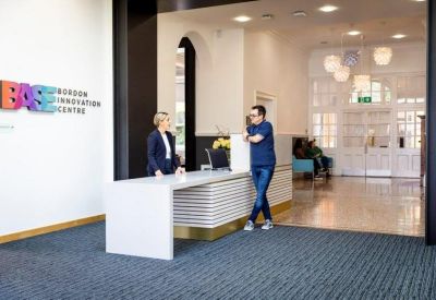 Modern white reception desk with colorful wall branding and friendly staff.