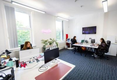 Bright open-plan office space with white desks and large windows.