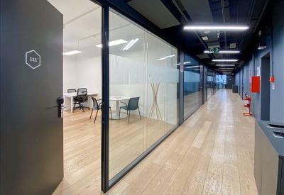 Modern office corridor featuring glass walls and wooden flooring.