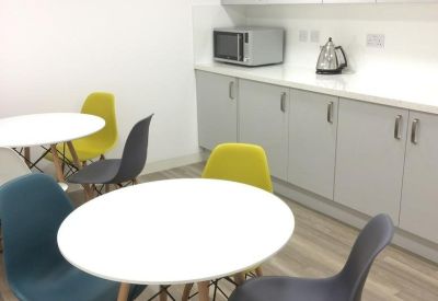 Communal kitchen and dining area with colorful chairs and modern grey cabinetry.