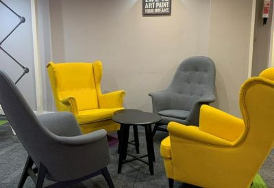 Colorful breakout area with yellow and grey wingback chairs and motivational wall art.