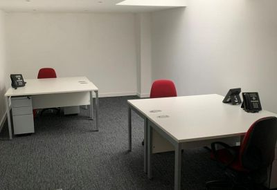 Simple private office suite with two white desks and red ergonomic chairs.