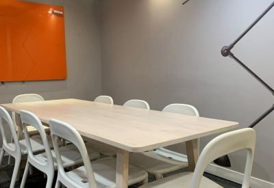 Bright meeting room with a light wood table, white chairs, and a sky-print ceiling.