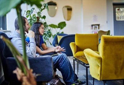 Vibrant breakout area with plush yellow armchairs and potted green plants.