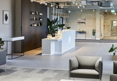 Modern reception lobby with white front desk and comfortable grey armchairs.