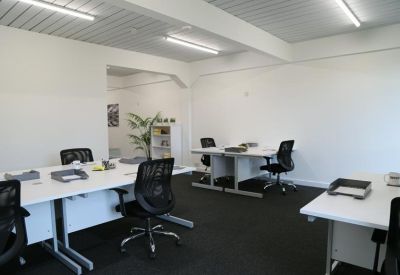 Spacious office with white desks, black ergonomic chairs, and large windows.