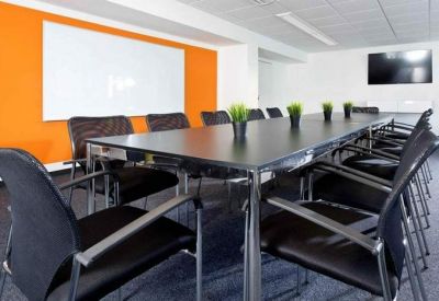 Professional conference room with a vibrant orange feature wall and long black meeting table.