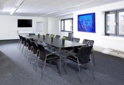 Spacious boardroom with a large black table, blue wall art, and ample natural light.