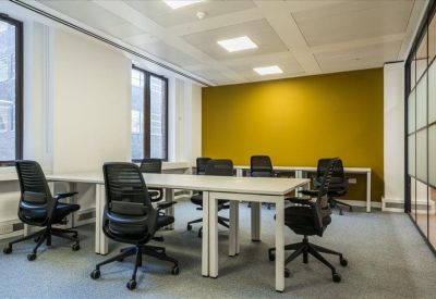 Shared workspace featuring white desks and a vibrant yellow accent wall.
