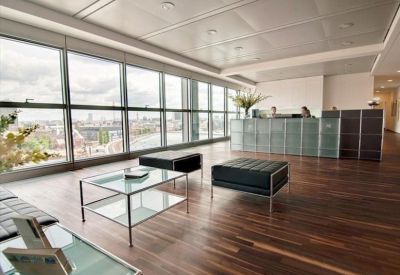 Bright reception area with wooden floors, glass coffee tables, and panoramic city views.