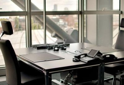 Executive office desk with ergonomic chairs and views of the city skyline through large windows.