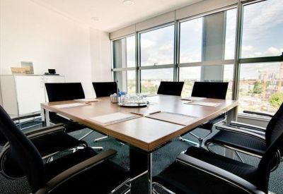 Modern conference room with a wooden table, black chairs, and floor-to-ceiling windows.