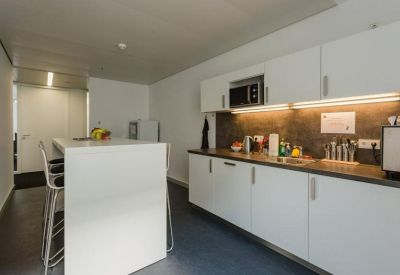 Modern communal kitchen with white cabinetry, a microwave, and a high breakfast bar.
