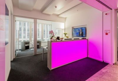 Modern reception desk with vibrant pink illumination and a wall-mounted monitor.