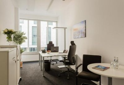 Private office suite with a white desk, ergonomic black chair, and large windows.