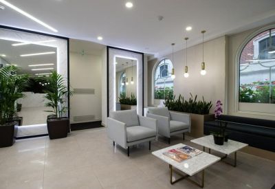 Lobby area featuring light grey armchairs, marble coffee tables, and large arched mirrors.
