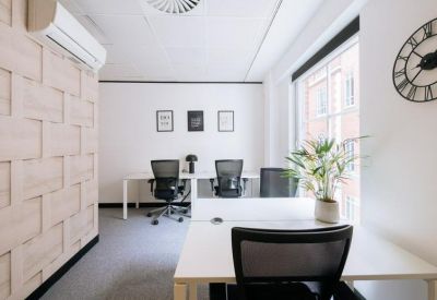 Private office suite with white desks, light wood paneled wall, and a decorative wall clock.