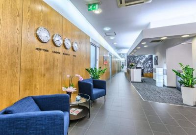 Bright reception area with wood-paneled walls, world clocks, and blue armchairs.
