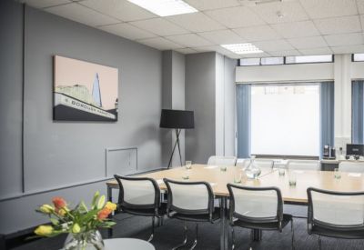 Bright boardroom with a light wood table, mesh-back chairs, and a contemporary framed skyline print.