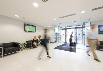 Bright lobby waiting area featuring black leather armchairs and glass entrance doors.