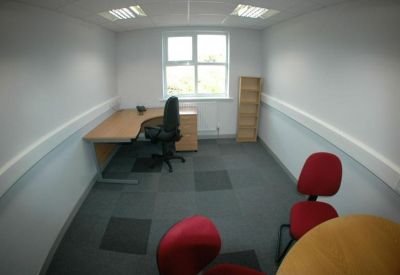 Small office suite with a corner desk, black task chair, and red visitor chairs.
