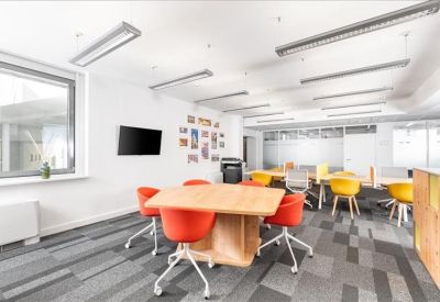 Vibrant coworking space with red and yellow chairs and a large wooden table.