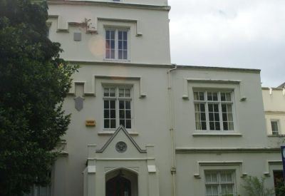 Portrait exterior view of the white facade and arched entrance at Braybrooke House, 4 Spencer Parade.