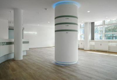 Reception area with wooden flooring and a large white circular pillar with green accents.