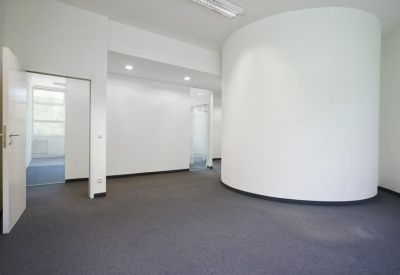 Spacious interior room featuring a unique curved white feature wall and dark carpeting.