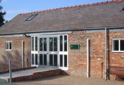 Main entrance to the building featuring large glass double doors and a brick ramp.