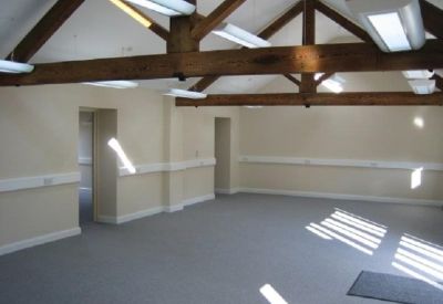Spacious open-plan office with exposed timber ceiling beams and neutral walls.