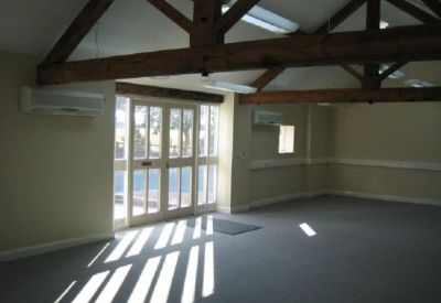 Large meeting room showing natural light through glass doors and vaulted timber ceilings.